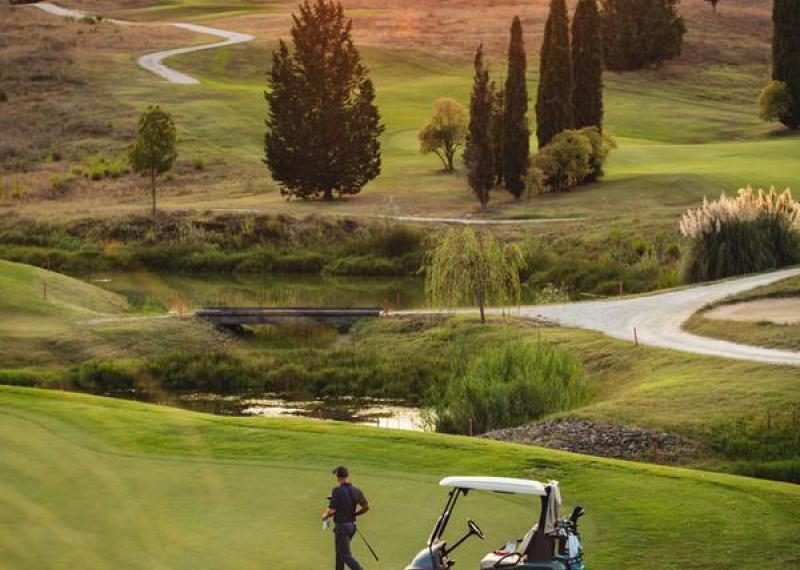 Castelfalfi golf course at sunset with player and golf car